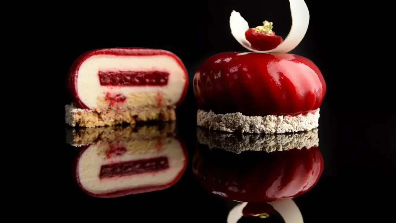 Un entremet rouge vif, miroir de la gourmandise. Une coupe révèle sa texture délicate, parfaite pour une recette entremet.