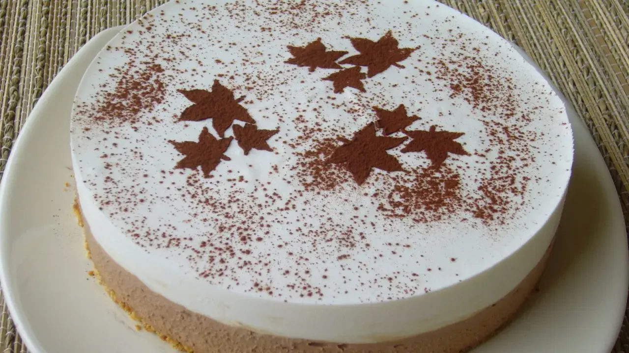Gâteau bicolore, blanc et chocolat, décoré de feuilles d'automne en cacao. Un dessert léger et gourmand pour célébrer l'automne.