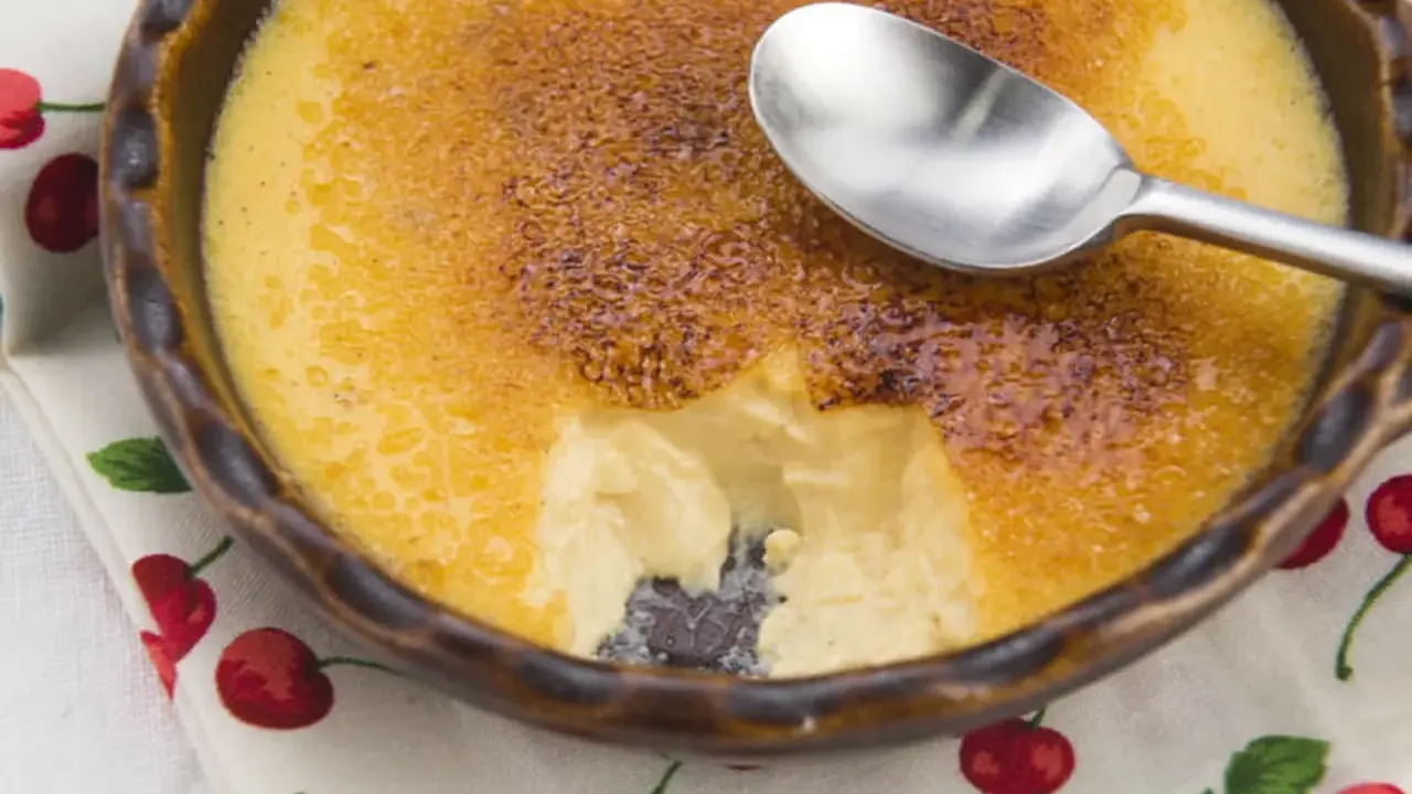 Crème brûlée avec une croûte caramélisée craquante. Une cuillère est posée sur le dessert, parfait pour une recette de crème brûlée facile et rapide.