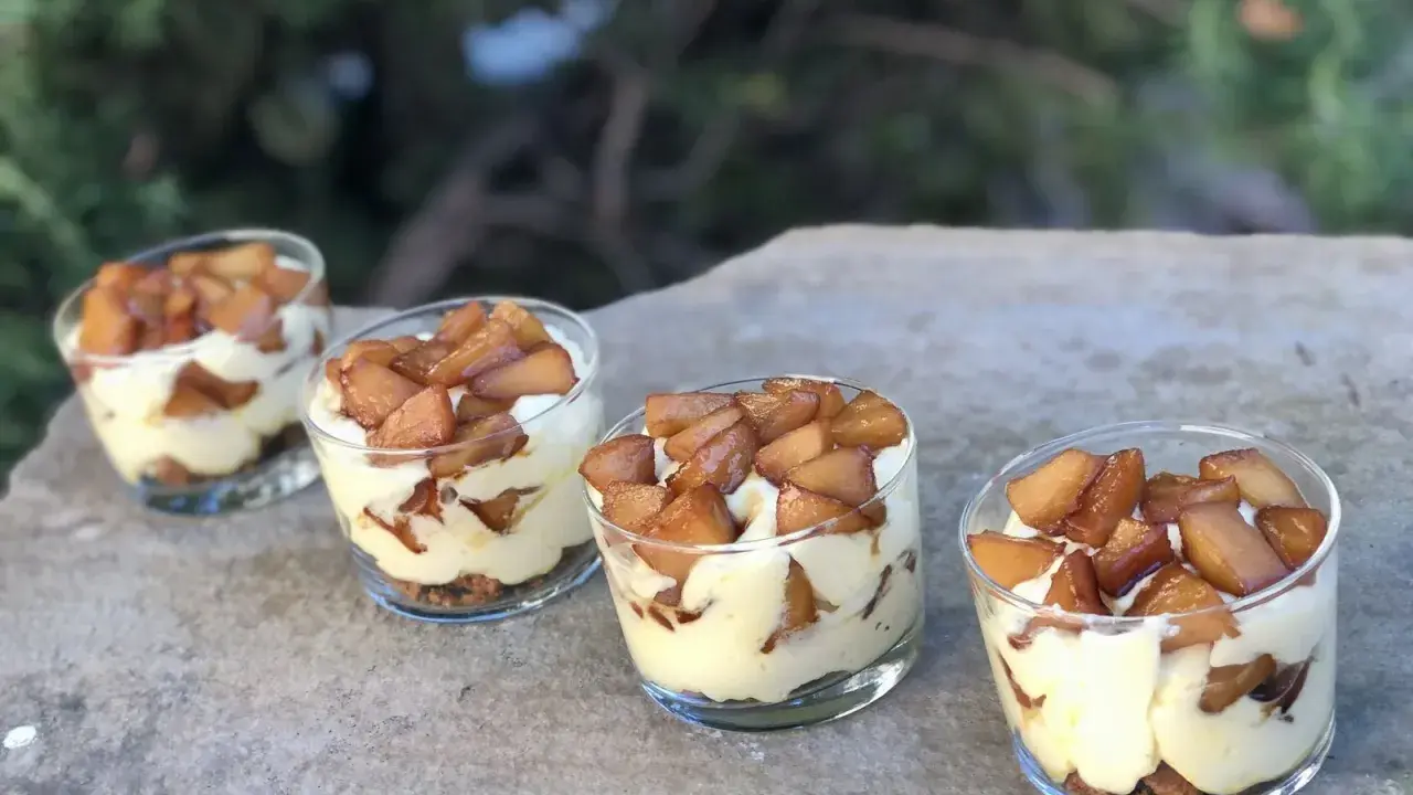 Quatre verrines mascarpone spéculoos, garnies de pommes caramélisées, sur une pierre.