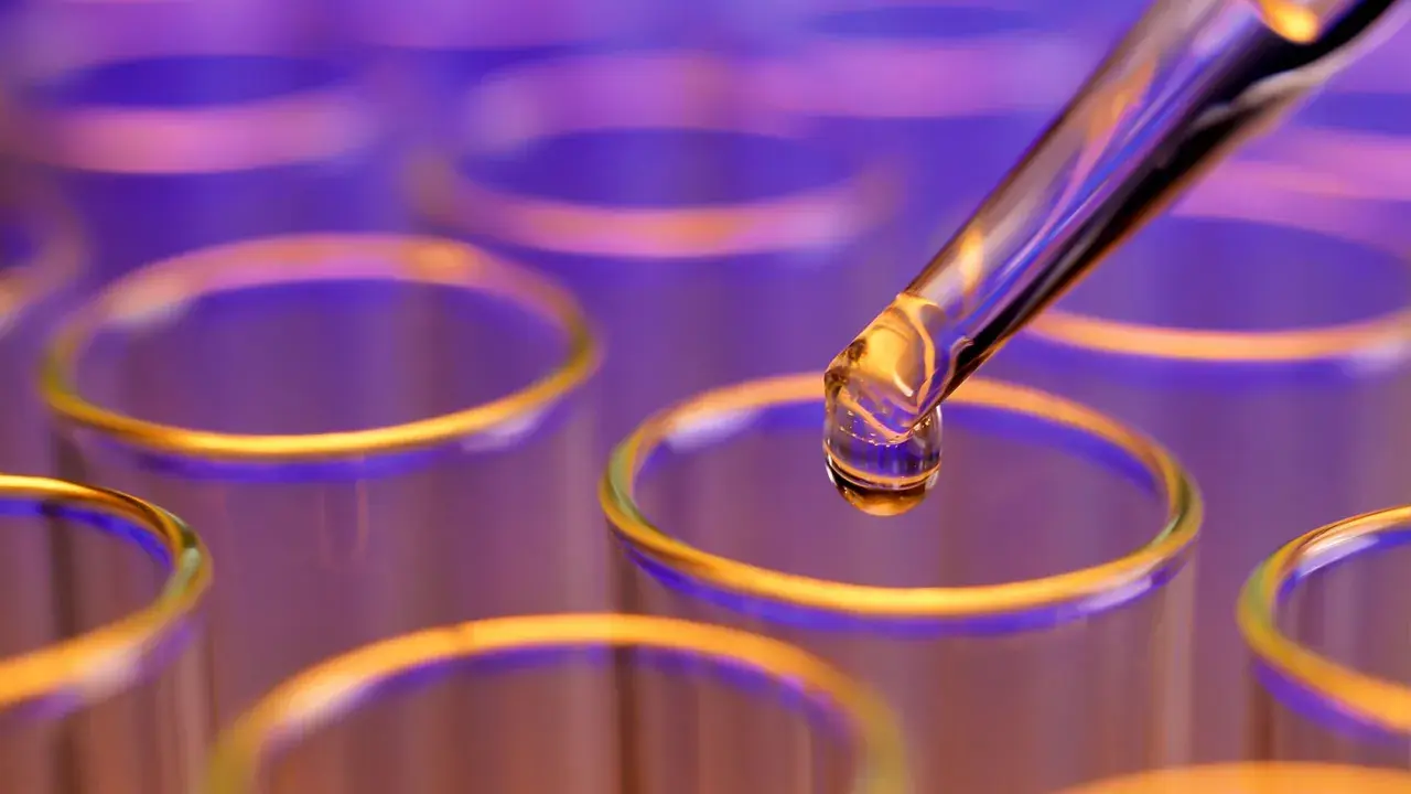 Goutte de colorant alimentaire liquide tombant d'une pipette dans un tube à essai.
