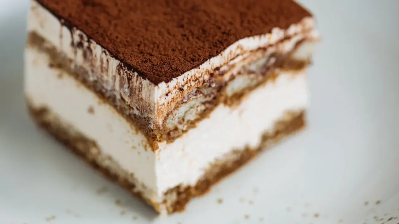 Une part de tiramisu onctueux, saupoudrée de cacao, prête à être dégustée. Une recette facile pour un dessert parfait.