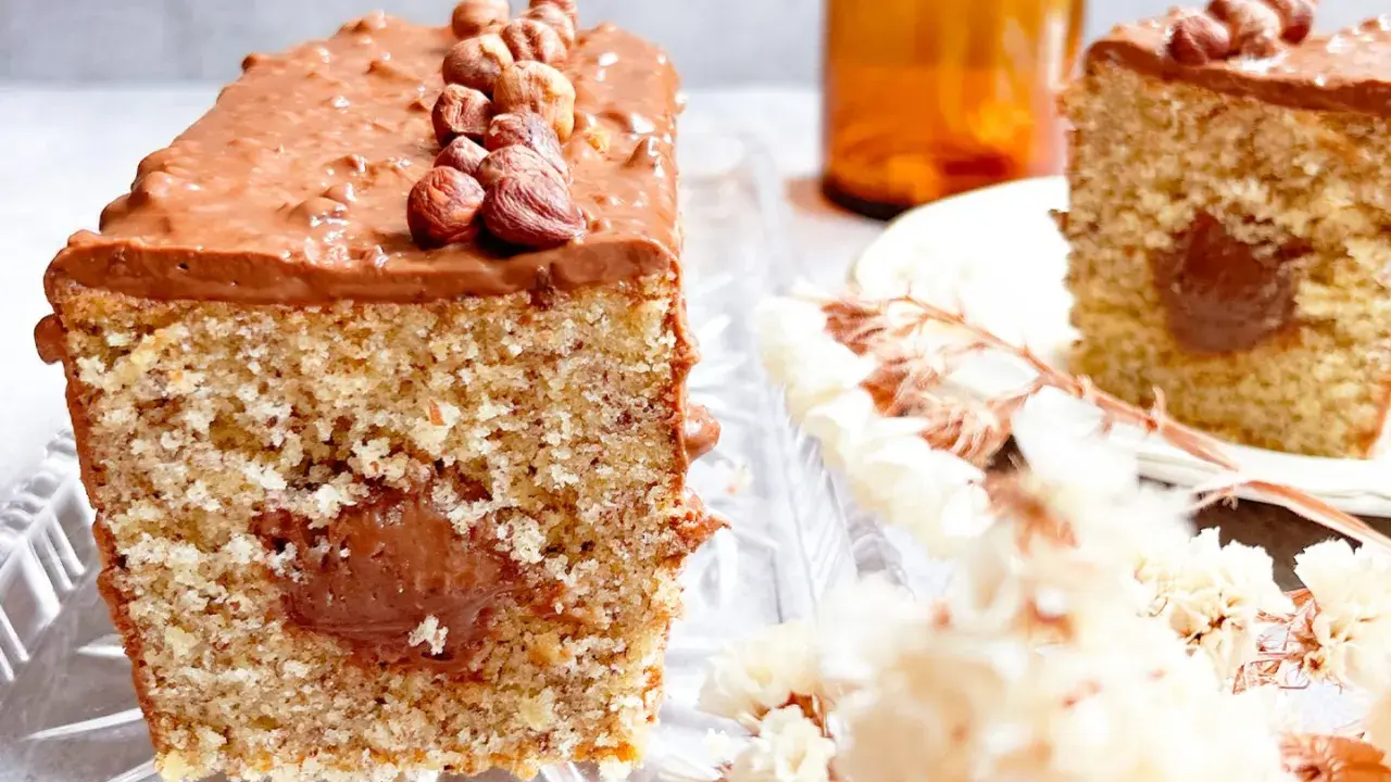 Gâteau moelleux avec un cœur coulant et un glaçage Nutella généreux, décoré de noisettes entières.