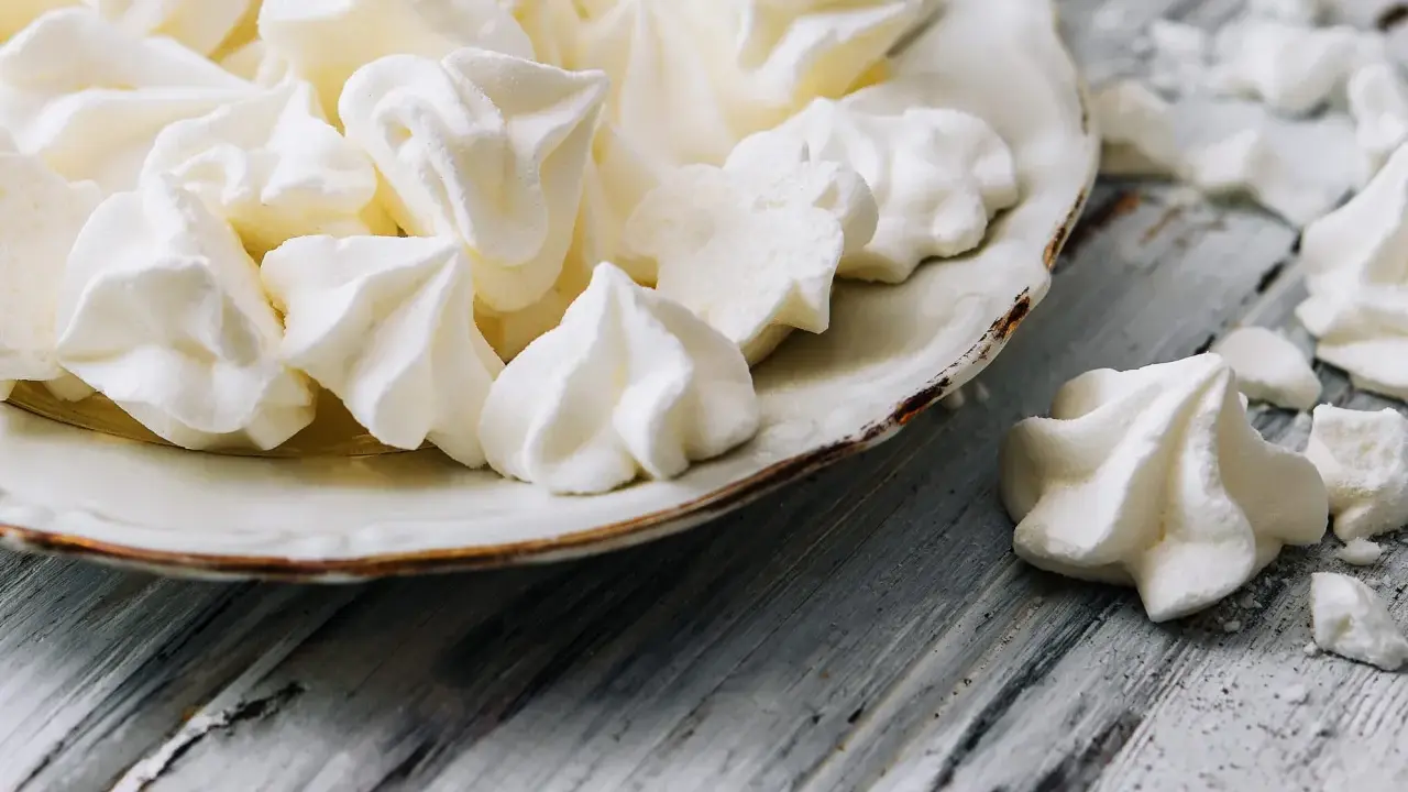 Douceur aérienne : des meringues comme celles de Cyril Lignac, croustillantes à souhait, sur une assiette vintage.