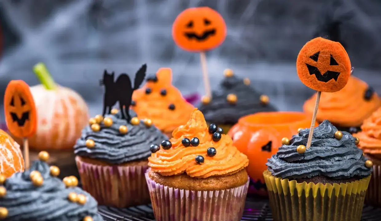 Cupcakes d'Halloween faciles décorés de glaçage orange et gris, de citrouilles et d'un chat noir. Parfait pour une fête effrayante !
