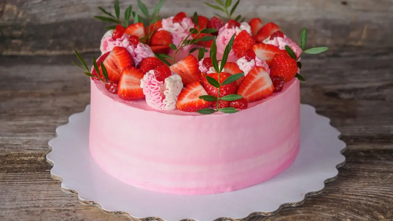Un délicieux gâteau fraise anniversaire rose, orné de fruits frais et de crème, prêt à célébrer un moment spécial.