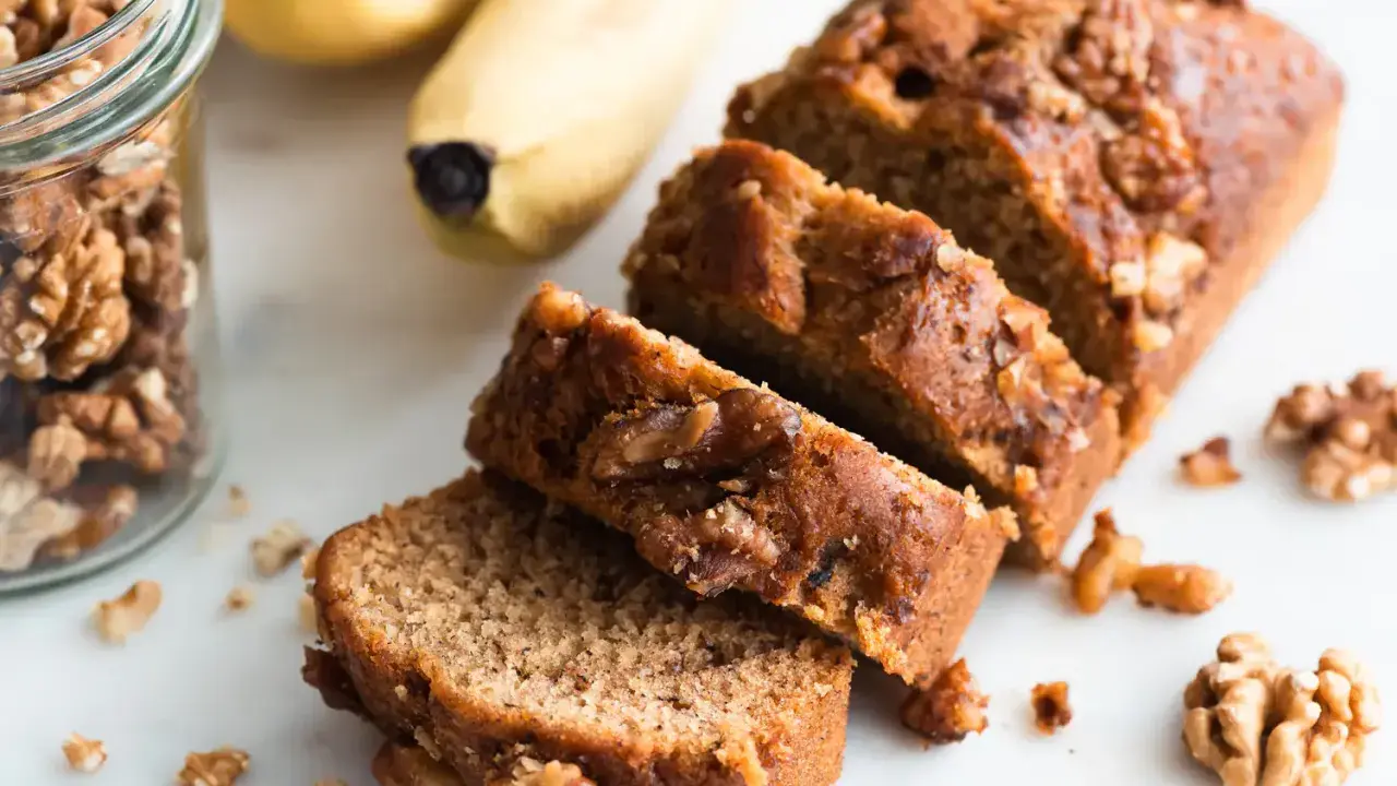 Tranches de délicieux dessert banane et noix, avec des bananes et des noix à proximité.
