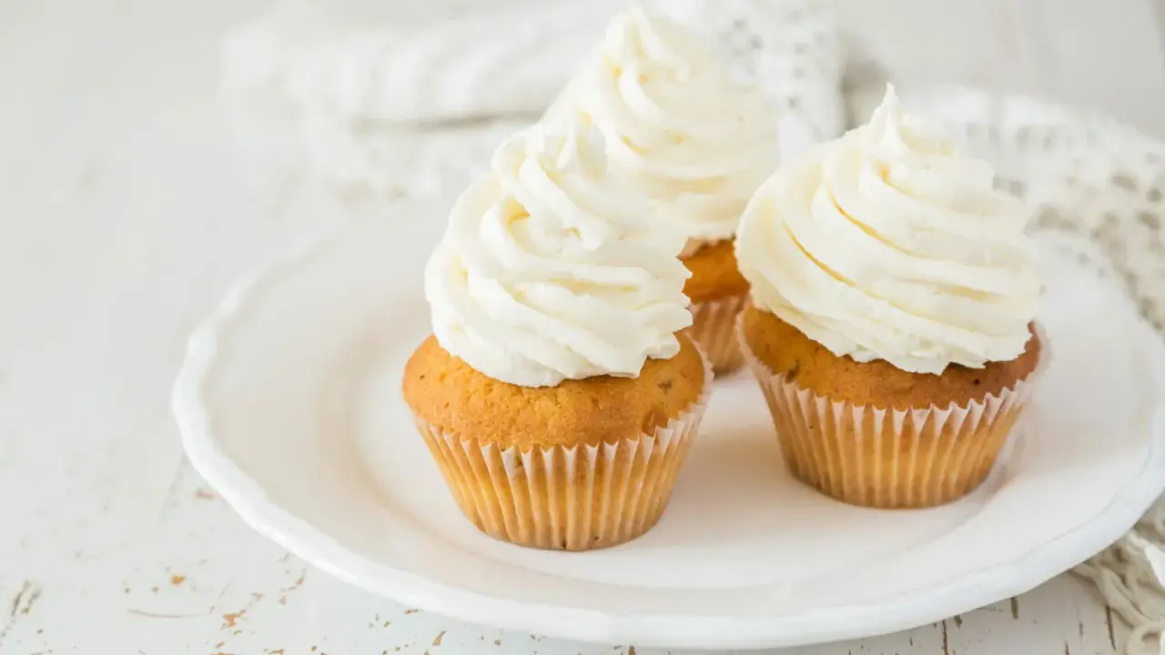 Trois cupcakes sur une assiette blanche, ornés d'un généreux glacage cupcake vanille.