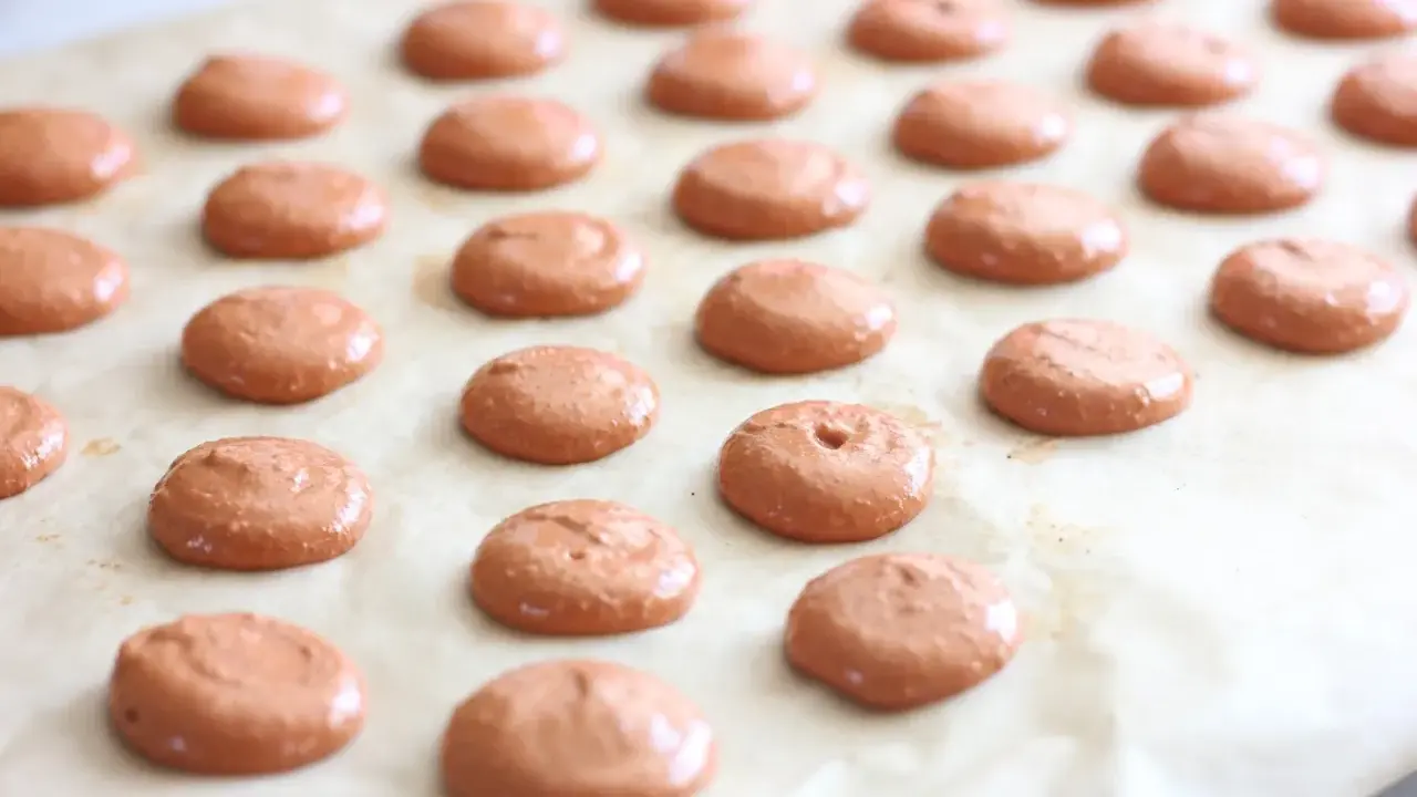 Des petites **collerettes macaron** marron clair, prêtes à être enfournées pour devenir de délicieux macarons.
