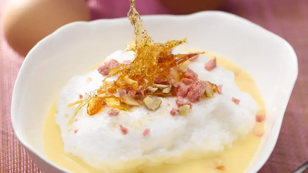Île flottante aérienne, une recette avec beaucoup d'œufs, garnie de caramel croquant et d'éclats roses.
