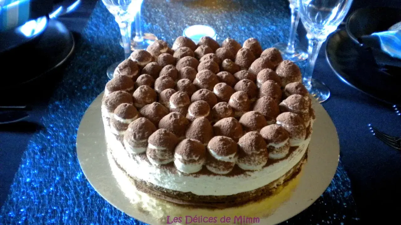 Un délicieux tiramisu revisité, parsemé de cacao, trône sur une table bleue scintillante, prêt à être dégusté.