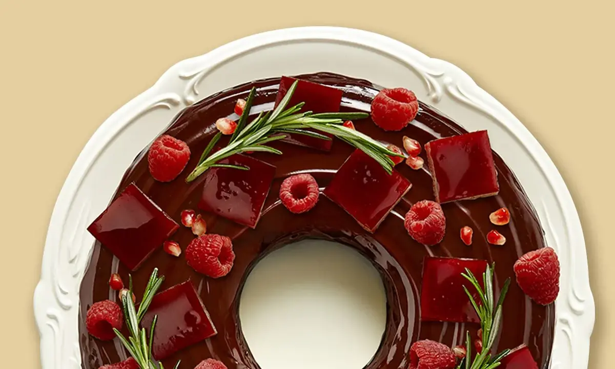 Gâteau angel cake au chocolat, décoré de framboises, de gelée rouge et de romarin.