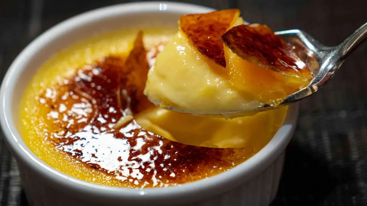 Une cuillère de crème brûlée, parfaite pour savoir que faire avec 4 jaunes d'œufs. La croûte caramélisée craque sous la cuillère.