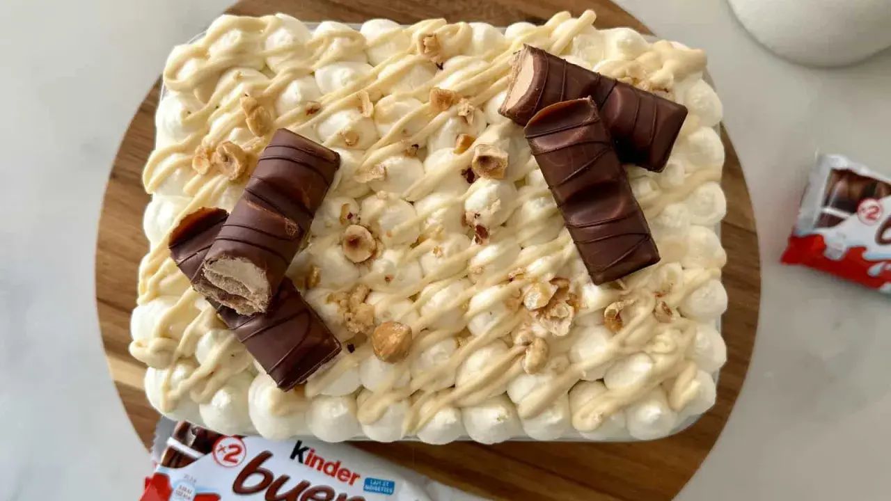 Un délicieux tiramisu Kinder Bueno, garni de morceaux de chocolat et de noisettes concassées. Un vrai régal pour les amateurs de chocolat !