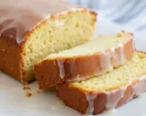Un délicieux gâteau courgette citron, nappé d'un glaçage blanc, est coupé en tranches sur une assiette blanche.