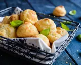 Gougères dorées dans un panier, garnies de feuilles de basilic. Si les vôtres ne gonflent pas, vérifiez la température du four !