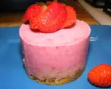 Gâteau individuel rose vif, garni de fraises fraîches. Un délice au glacage fraise sur fond bleu.