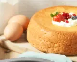 Un savarin traditionnel, doré et moelleux, garni de crème fouettée et de fruits rouges. Des œufs et de la farine sont prêts pour la préparation.