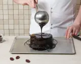 Un chef verse un glaçage au chocolat brillant sur un gâteau rond. Le glaçage sur gâteau froid ou chaud coule parfaitement, créant une finition miroir.