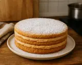 Gâteau à trois étages garni de crème onctueuse, saupoudré de sucre glace. Une délicieuse recette avec biscuit écrasé pour un dessert parfait.