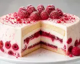 Gâteau à étages blanc et rose, garni de framboises fraîches et de poudre de framboise. Un délice fruité !