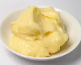 Crème pâtissière onctueuse, légèrement granuleuse, dans un bol blanc. Des points noirs de vanille parsèment la texture crémeuse.