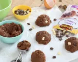 Pâte à cookies au chocolat prête à être façonnée. Des pépites de chocolat et un sachet "comment faire des pépites de chocolat" sont à proximité.