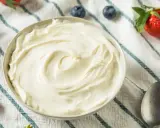 Un bol de crème mascarpone onctueuse, garni de fraises et de myrtilles, prêt à être dégusté.