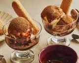 Deux coupes de glace tiramisu, saupoudrées de cacao, avec des biscuits à la cuillère. Un délice glacé à savourer.
