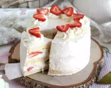Un délicieux layer cake fraise, garni de crème fouettée et de fraises fraîches, prêt à être dégusté.
