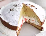 Un délicieux victoria cake, saupoudré de sucre glace, révèle sa garniture crémeuse et sa confiture de fruits rouges.