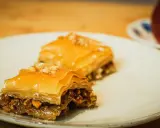 Deux parts de baklava, garnies de noix, sur une assiette. Une recette de baklava qui fait saliver.