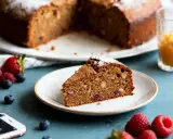 Tranche de gâteau aux noix et fruits rouges, saupoudrée de sucre glace. Une option saine pour un dessert, peut-être préparée avec de la **stevia pour gâteau**.