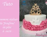 Gâteau d'anniversaire en pâte à sucre blanc orné d'une couronne dorée et d'un "froufrou" rose.