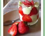 Un délicieux tiramisu pistache fraise, présenté en verrine avec des fraises fraîches sur le côté.