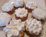 Plusieurs tartelettes garnies de crème citronnée et couronnées de meringue italienne aux formes variées.