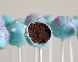 Gourmandes boules de chocolat bleu ciel, décorées de vermicelles roses ou d'étoiles blanches. Une recette facile de cake pop à dévorer !