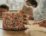 Une main coupe une part d'un gâteau coloré de vermicelles. Apprenez comment couper un layer cake pour un partage parfait.