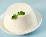 Un dôme de ricotta crémeuse, garni d'une feuille verte, sur une assiette blanche. Découvrez les ricotta bienfaits pour une alimentation saine.
