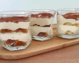 Quatre verrines de tiramisu chantilly mascarpone, superposant biscuits imbibés et crème onctueuse, saupoudrées de cacao.