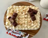Un délicieux tiramisu Kinder Bueno, garni de morceaux de chocolat et de noisettes concassées. Un vrai régal pour les amateurs de chocolat !