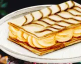 Un délicieux gâteau sec français traditionnel, un mille-feuille aux couches croustillantes et à la crème onctueuse, décoré de volutes de chocolat.