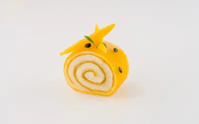 Un adorable petit roulé jaune, décoré comme un animal, montre ce que faire avec de la purée de fruits.