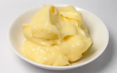 Crème pâtissière onctueuse et dorée, prête à garnir éclairs et millefeuilles. Petits points noirs de vanille visibles.