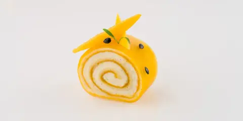 Un adorable petit roulé jaune, décoré comme un animal, montre ce que faire avec de la purée de fruits.