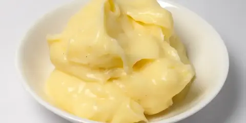 Crème pâtissière onctueuse et dorée, prête à garnir éclairs et millefeuilles. Petits points noirs de vanille visibles.