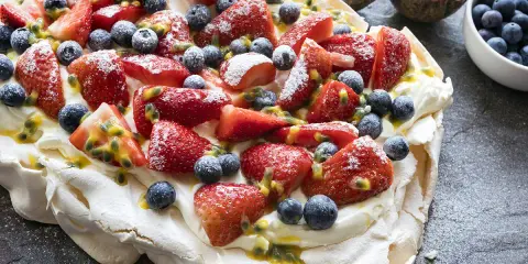 Pavlova inratable garnie de fraises, myrtilles et fruits de la passion. Un délice croustillant à l'extérieur et moelleux à l'intérieur.