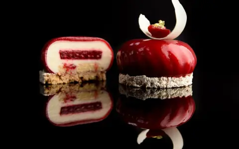 Un entremet rouge vif, miroir de la gourmandise. Une coupe révèle sa texture délicate, parfaite pour une recette entremet.