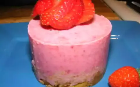 Gâteau individuel rose vif, garni de fraises fraîches. Un délice au glacage fraise sur fond bleu.
