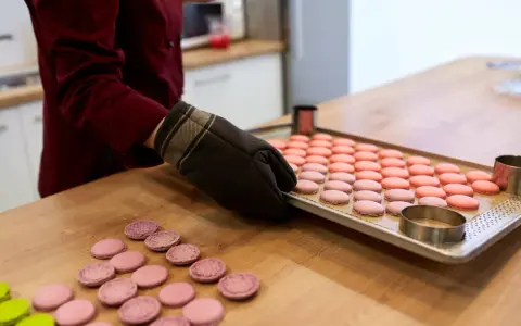 Préparation pour la cuisson macaron four traditionnel : une plaque de macarons roses et roses est prête, des cercles à pâtisserie sont à proximité.
